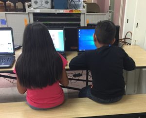 boy and girl on computers playing our games