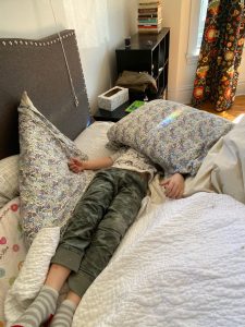 Student on bed with pillow over her head